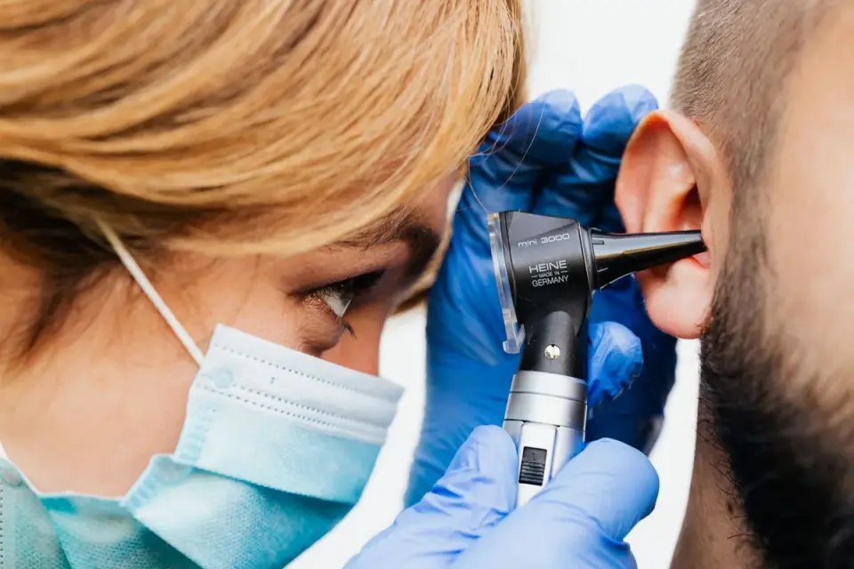 Doctor using an otoscope to examine a patient's ear during a hearing evaluation