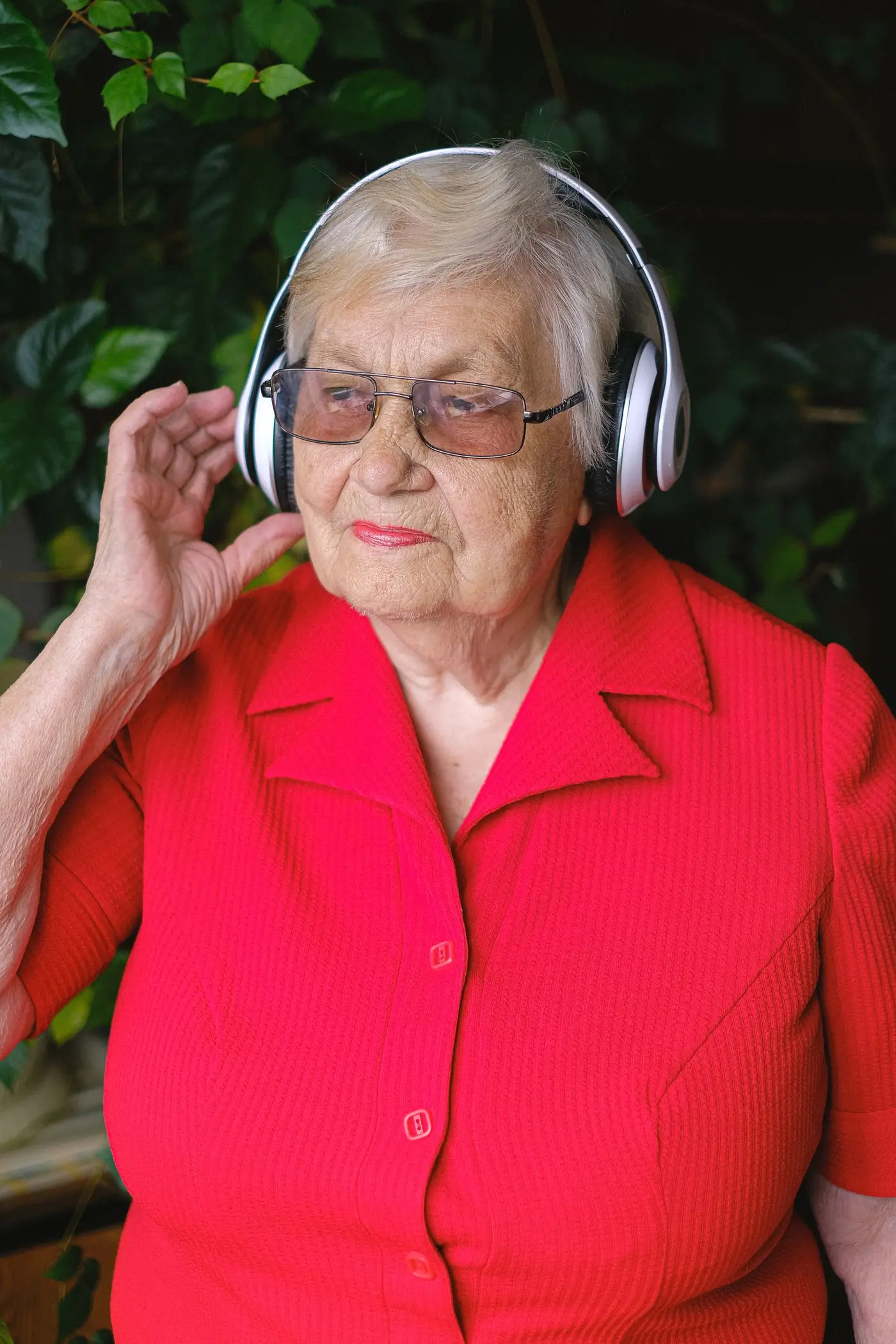 Senior woman with wireless headphones in a garden, illustrating better hearing health in daily life