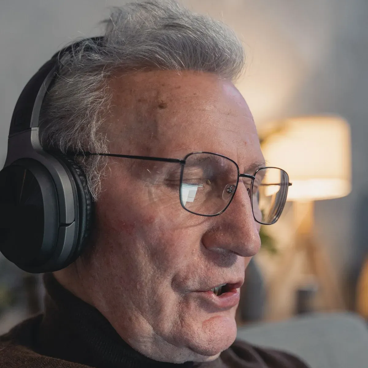 Older man wearing over-ear headphones during a first hearing test, listening carefully for the softest tones