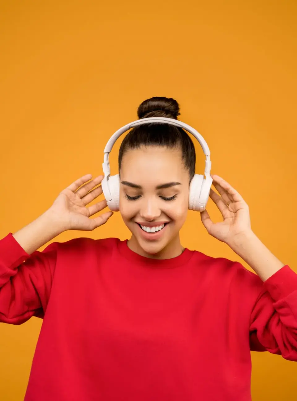 Young woman listening to music through large over-ear headphones at high volume, a common cause of noise-induced hearing loss in adults under 40