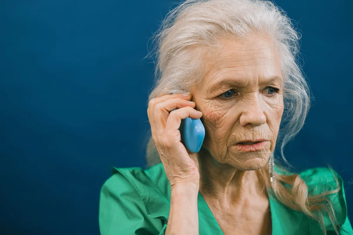 Older woman holding a mobile phone to her ear during a call — struggling with phone conversations is a common warning sign of hearing loss